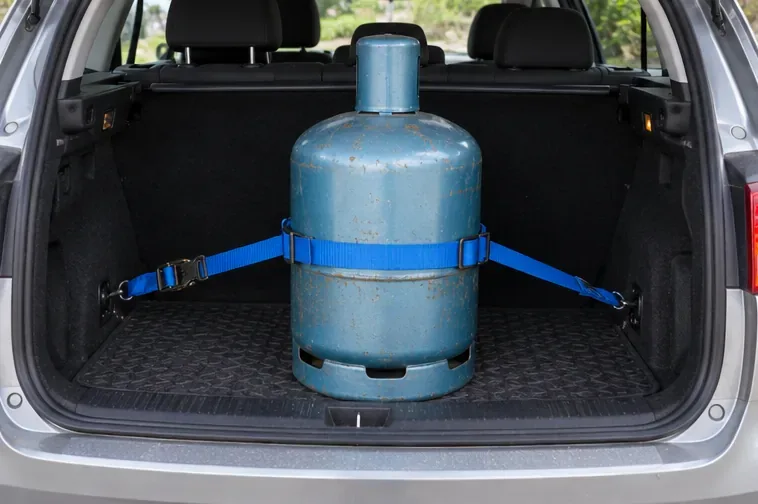 Une bouteille de gaz maintenue debout et attachée dans le coffre d’une voiture