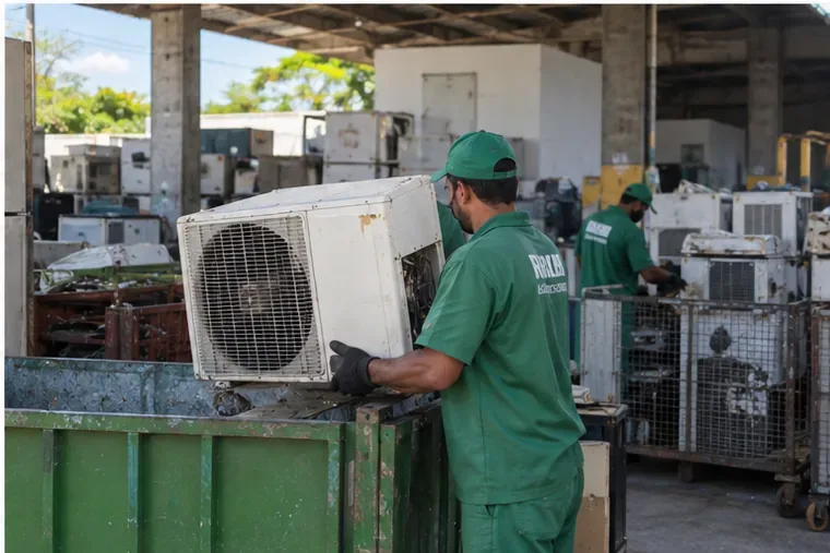 Trabalhadores recebem unidades externas de ar-condicionado usadas em uma instalação de triagem e reciclagem