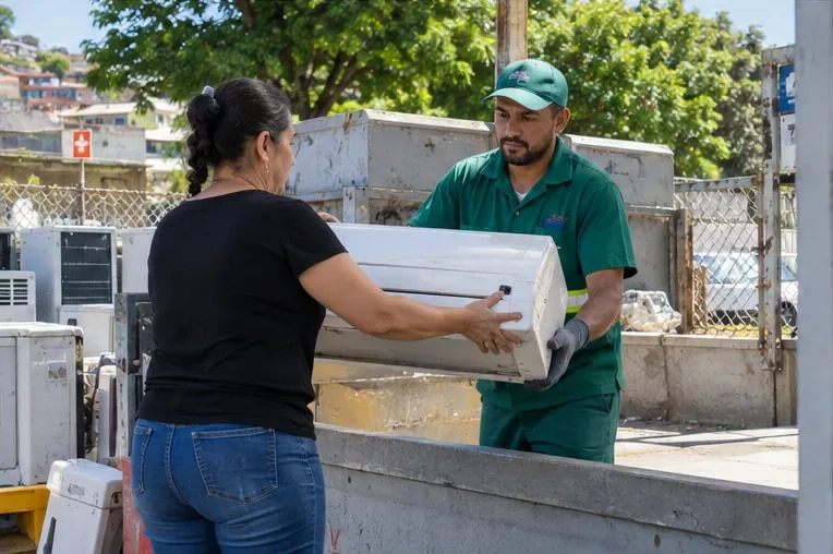 Pessoa entrega uma unidade interna de ar-condicionado a um trabalhador em um ponto de recebimento de equipamentos.