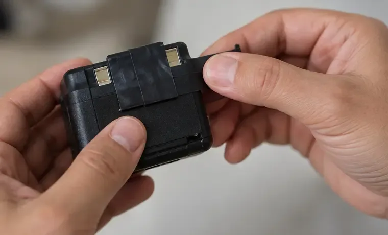 Mãos cobrindo os terminais metálicos de uma bateria de lítio íntegra com fita isolante