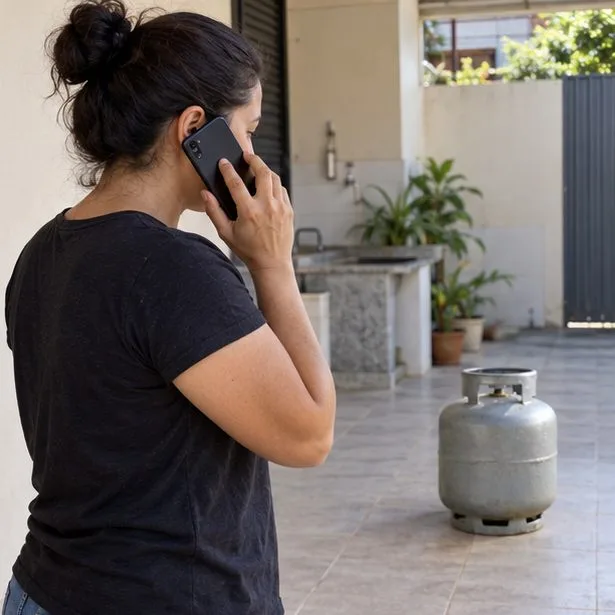Moradora fala ao celular mantendo distância de um botijão parado no chão