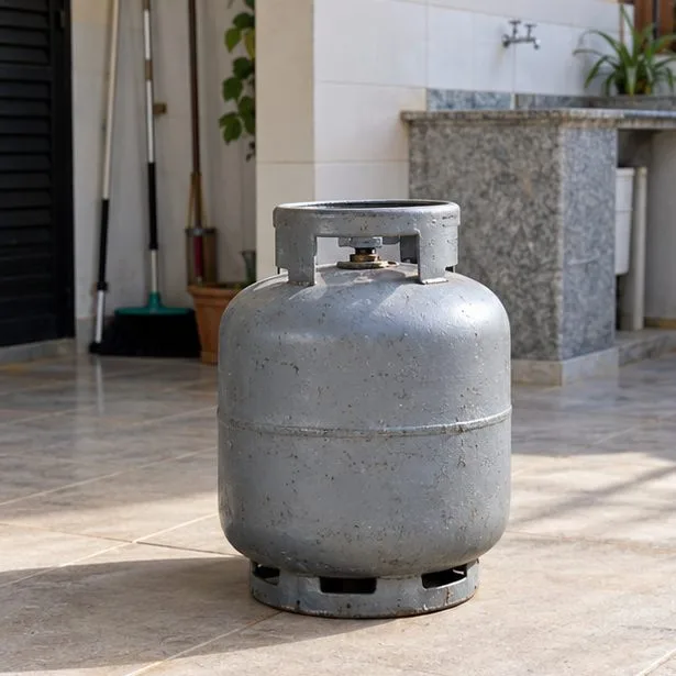 Botijão doméstico cinza em pé, sem mangueira conectada, em área coberta e ventilada