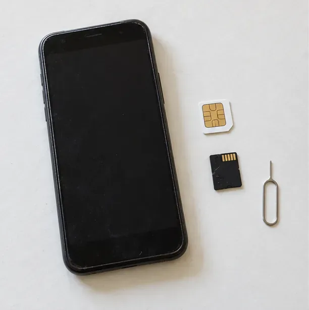 Um celular desligado ao lado de um cartão SIM, um cartão microSD e uma ferramenta de ejeção.