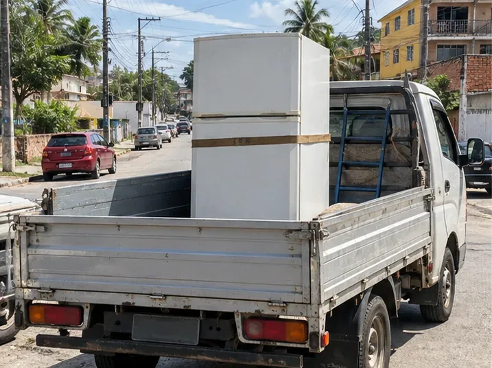 Geladeira presa na vertical na carroceria de um veículo de transporte em rua urbana