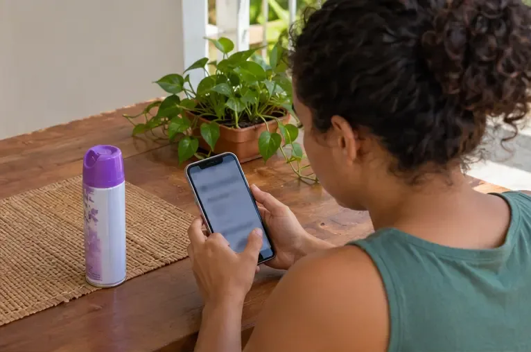 Pessoa consulta o celular ao lado de uma lata de spray intacta para verificar o canal de descarte.