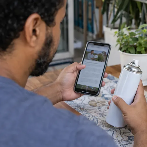 Pessoa consultando uma página de serviço público no celular enquanto segura uma lata de spray intacta