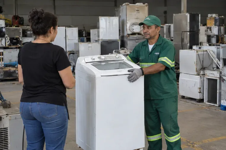 Pessoa entregando uma máquina de lavar a um trabalhador em um centro de recebimento de eletrodomésticos