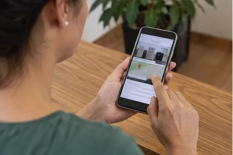 Pessoa usando o celular para consultar um mapa e informações de pontos de coleta