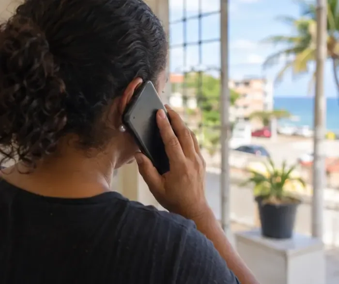 Moradora fala ao telefone para confirmar o serviço municipal de coleta de uma máquina de lavar.