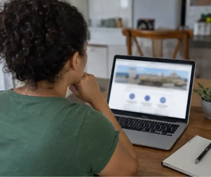 Moradora consulta em um notebook uma página de serviço público sobre o descarte correto da máquina de lavar.