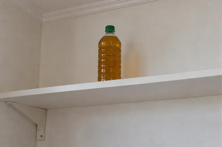 Garrafa tampada com óleo usado fica em uma prateleira alta e seca, afastada do chão