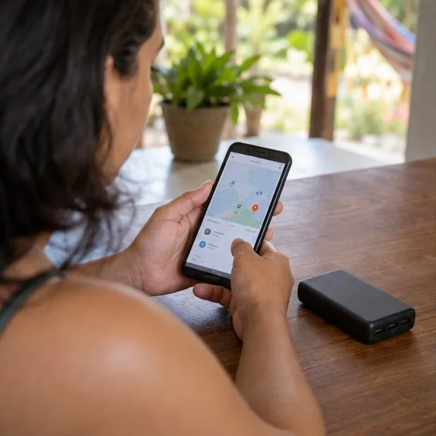 Pessoa consulta o celular ao lado de um power bank antes de escolher um local de entrega.