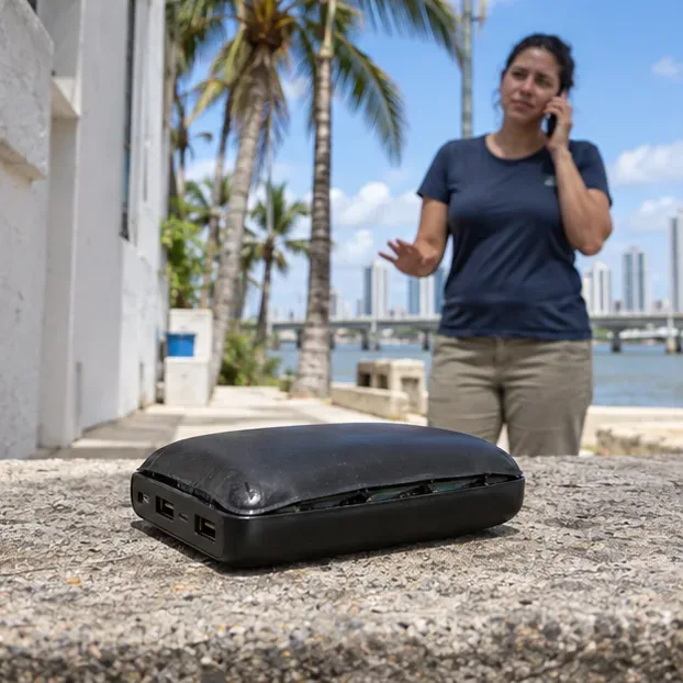 Power bank visivelmente estufado isolado em uma superfície segura enquanto uma pessoa busca orientação por telefone