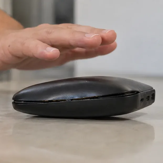 Mão mantida acima de um power bank muito estufado, sem apertar nem tentar abrir a carcaça