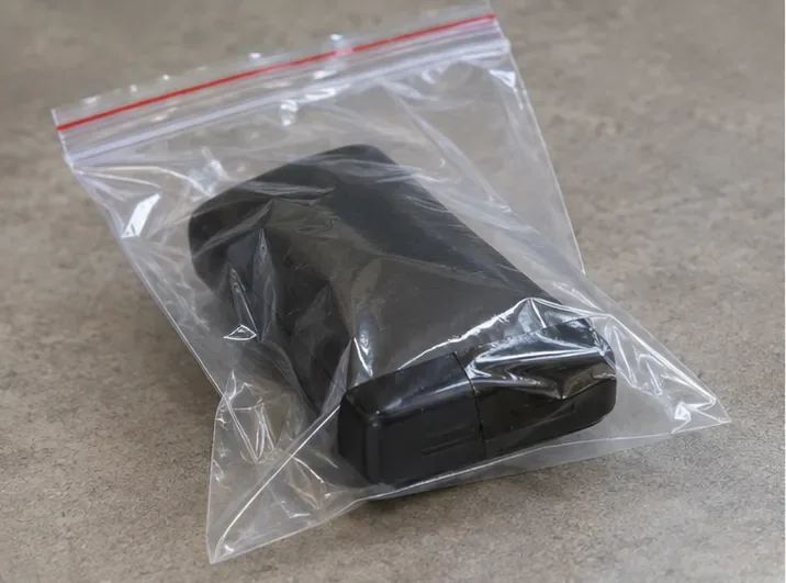 Power bank deformado acondicionado sozinho em um saco plástico transparente sobre uma bancada.