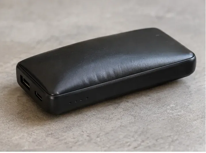Power bank preto com a carcaça visivelmente abaulada sobre uma superfície não inflamável.