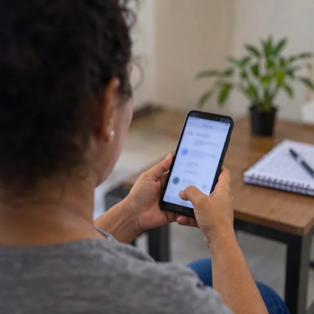 Morador usando um celular para consultar o serviço de retirada de móveis, sem detalhes legíveis na tela.