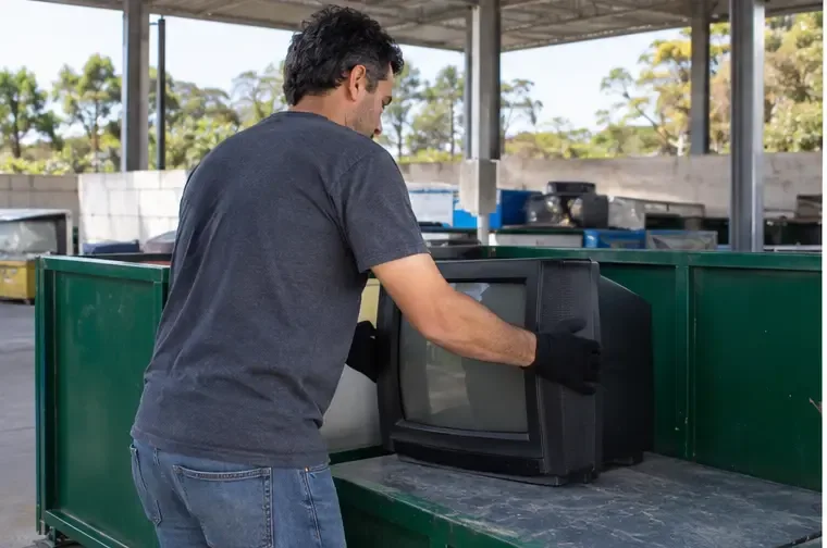 Morador colocando uma televisão antiga em uma área coberta destinada a equipamentos eletrônicos