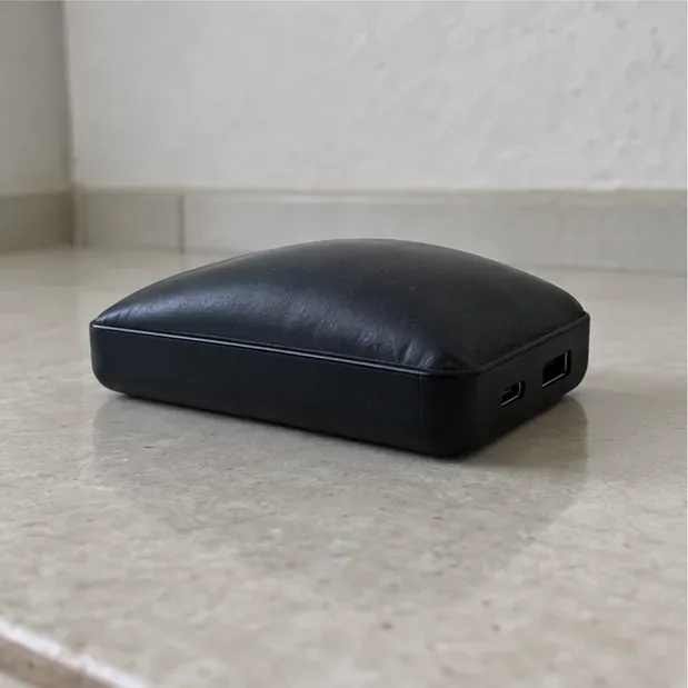 Power bank estufado apoiado sozinho em uma superfície cerâmica seca, em área livre de objetos.