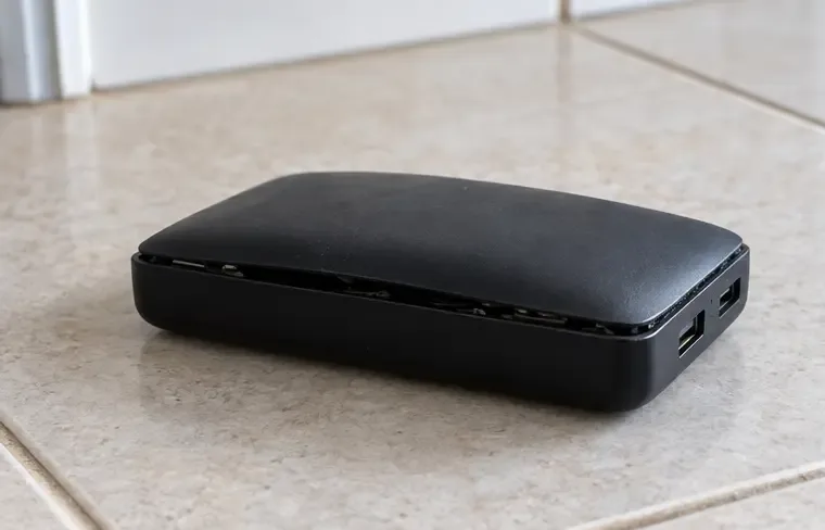 Um power bank preto apresenta a carcaça levantada e separada na lateral, sinal visual de estufamento.