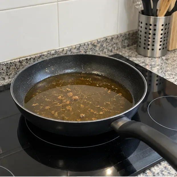 Sartén con aceite de cocina usado enfriándose sobre una placa antes de guardarlo para reciclar