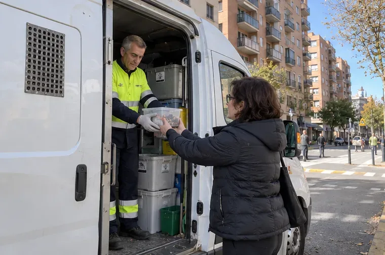 Vecina entregando un recipiente con pilas usadas al personal de una deixalleria móvil en una calle urbana