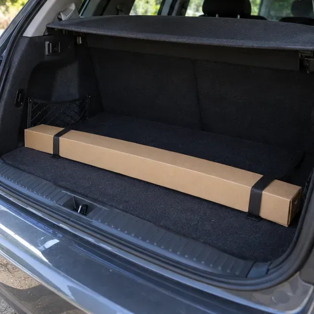 Un tubo fluorescente dentro de una caja larga de cartón, colocado horizontalmente y sujeto en el maletero