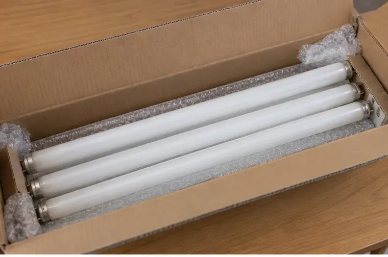 Varios tubos fluorescentes colocados en una caja de cartón con material de protección para evitar golpes