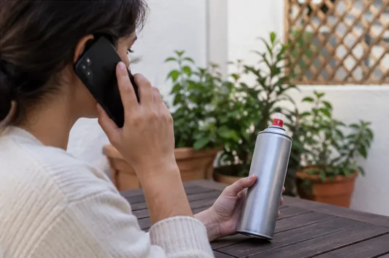 Una persona consulta por teléfono mientras sostiene un aerosol intacto que todavía puede contener producto