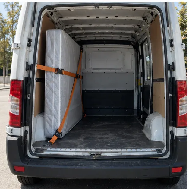 Un colchón protegido va sujeto con una cincha dentro de una furgoneta para transportarlo de forma estable