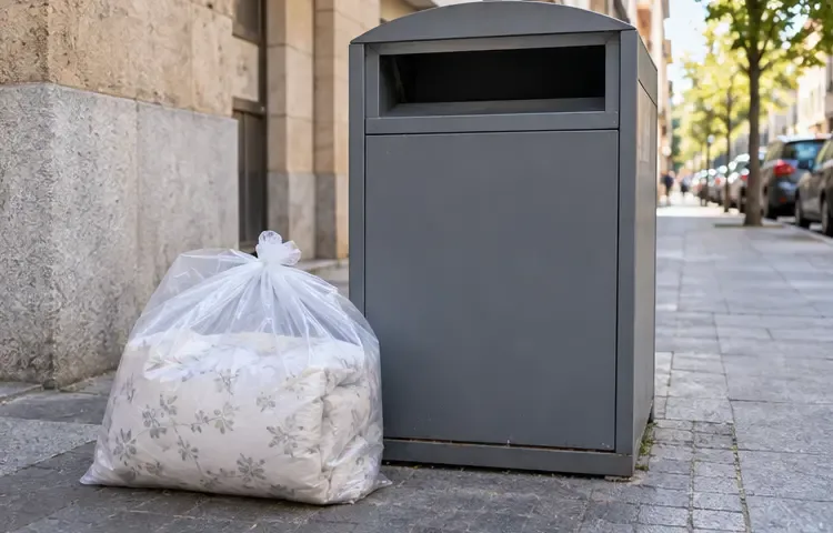 Un edredón plegado dentro de una bolsa junto a un contenedor textil en una calle urbana