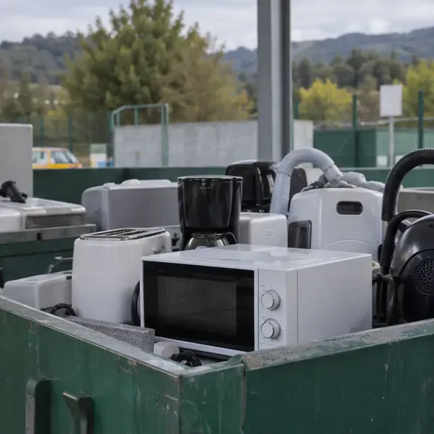 Un microondas colocado entre otros pequeños electrodomésticos en una zona ordenada de reciclaje