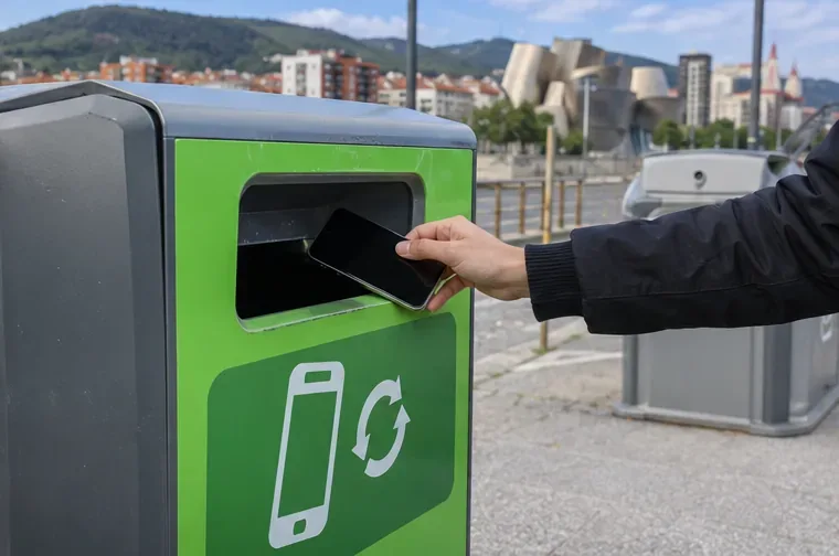 Persona depositando un teléfono móvil en un contenedor específico para recogida de aparatos electrónicos