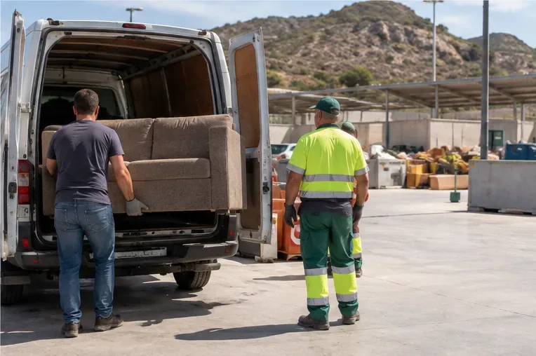 Un sofá descargándose de una furgoneta en una instalación de recepción de residuos voluminosos