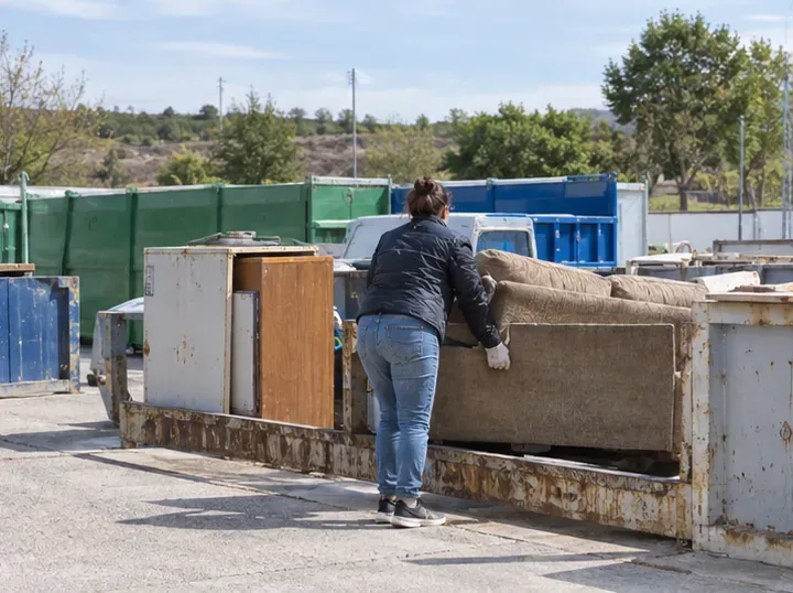 Persona deposita un sofá en una zona de residuos voluminosos de un punto limpio