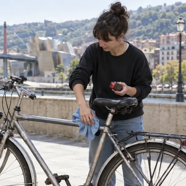 Persona limpiando el sillín y retirando un accesorio pequeño de una bicicleta
