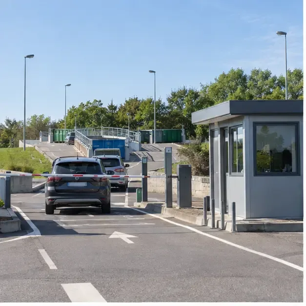 Entrée d’une déchèterie municipale avec voie d’accès, barrières et conteneurs de tri