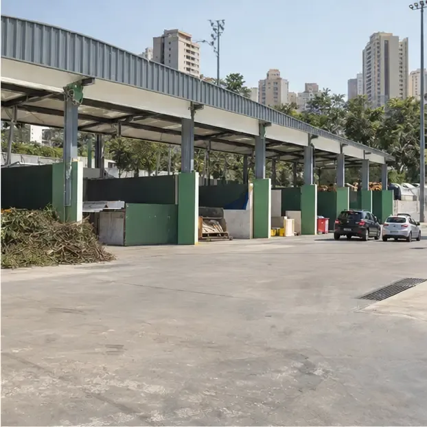 Vista externa de uma estação municipal de coleta com baias cobertas e áreas separadas para diferentes materiais