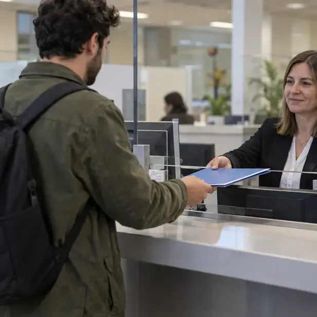 Persona entregando una carpeta de documentos a una empleada en un mostrador de atención municipal