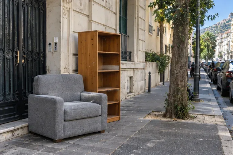 Un fauteuil et une bibliothèque déposés près de l'entrée d'un immeuble dans une rue niçoise