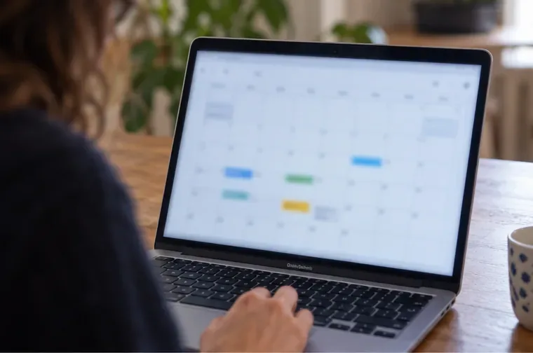 Une personne consulte un calendrier flou sur l’écran d’un ordinateur portable