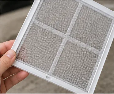 Hands inspecting the fine mesh and frame of a clean dehumidifier filter for damage