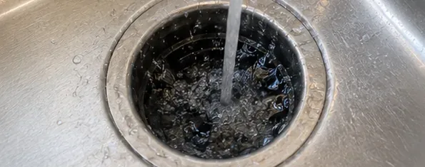 Cold water flushing the garbage disposal opening after the ice cleaning cycle.