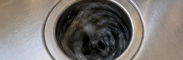A top-down view of ice moving inside a running garbage disposal during the cleaning cycle.