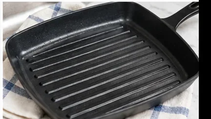 A clean dark grill pan resting on a dry kitchen towel after washing
