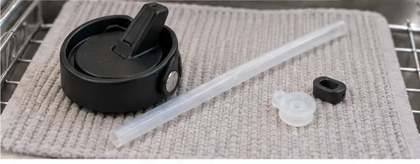 A straw lid, clear straw, and small seal pieces spread on a clean towel to air dry