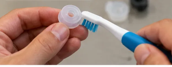 A small removable silicone seal being gently cleaned with a soft brush