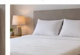 A neatly made bed with a clean white mattress topper covered by fresh bedding