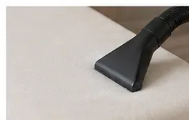 An upholstery vacuum attachment moving gently across the white surface of a memory foam mattress topper