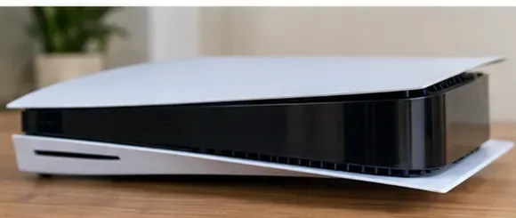 A PS5 console lying horizontally on a clear wooden work surface with its covers still attached.